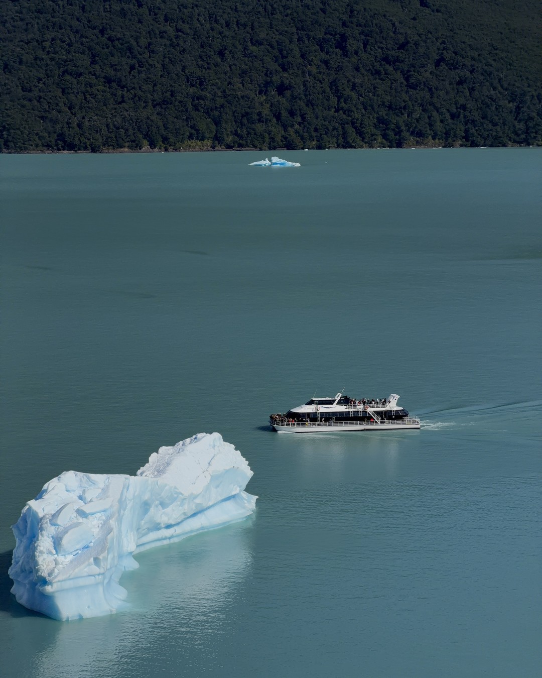 A tour boat passing an iceberg in front of Perito Moreno Glacier