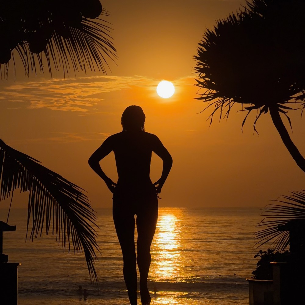 A silhouette framed by trees at sunrise on the beach in Da Nang