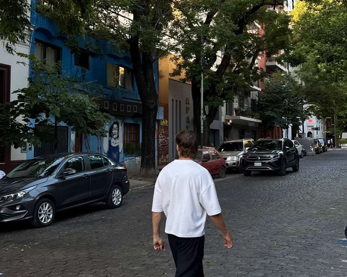 Daniel walking along a tree-lined cobbled street in Palermo, Buenos Aires