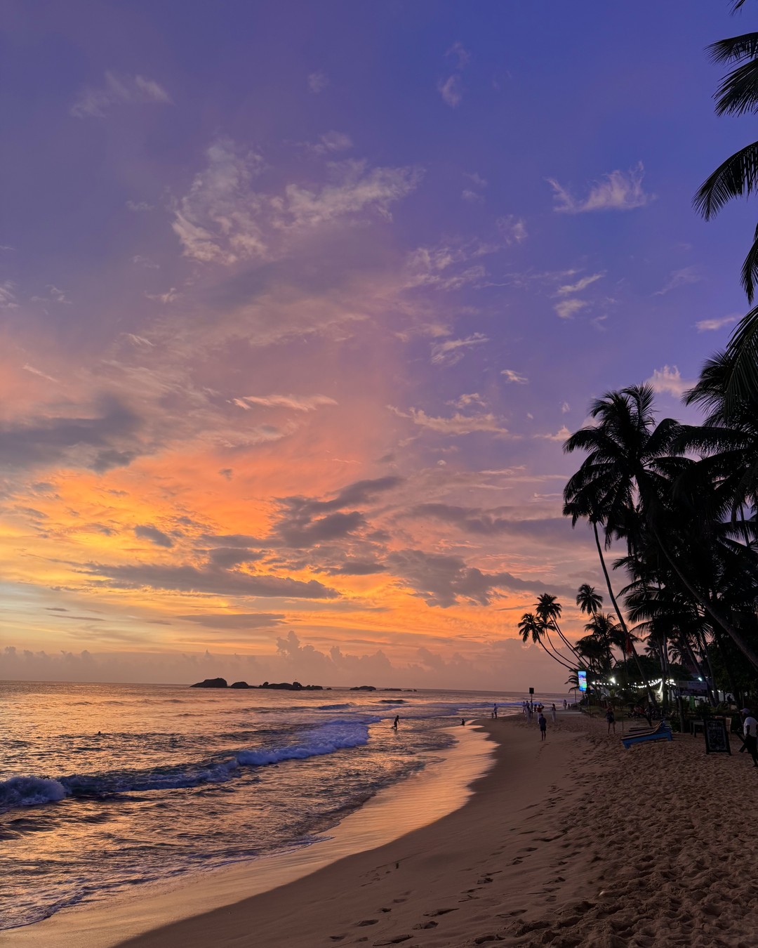 Sunset over the sea with a storm cloud and palm silhouettes on the south coast of Sri Lanka