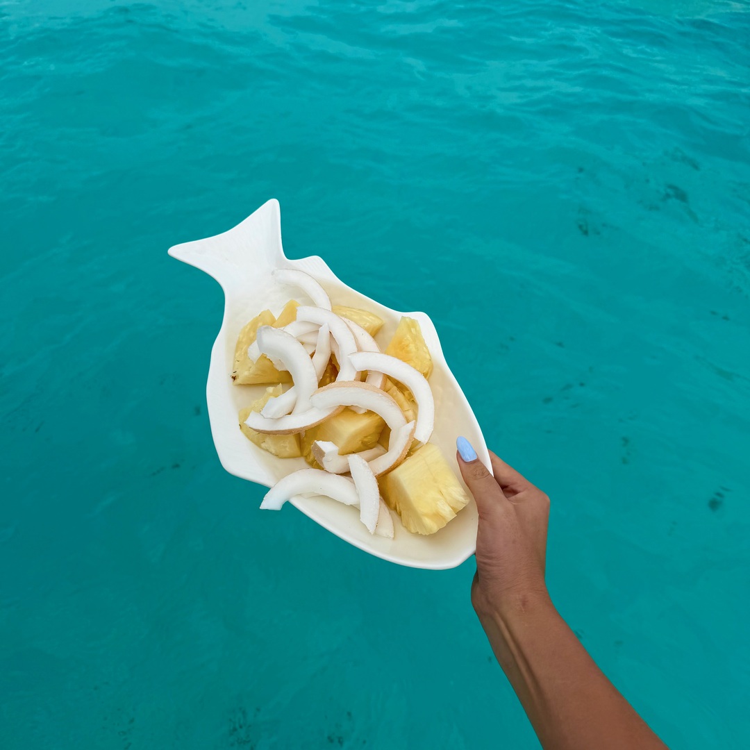 Fresh coconut and pineapple above turquoise water after snorkelling near Mnemba Island
