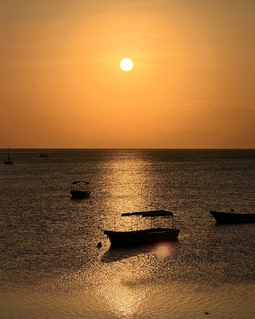 Golden sunset over the sea and boats off Nungwi, photographed from Maisha
