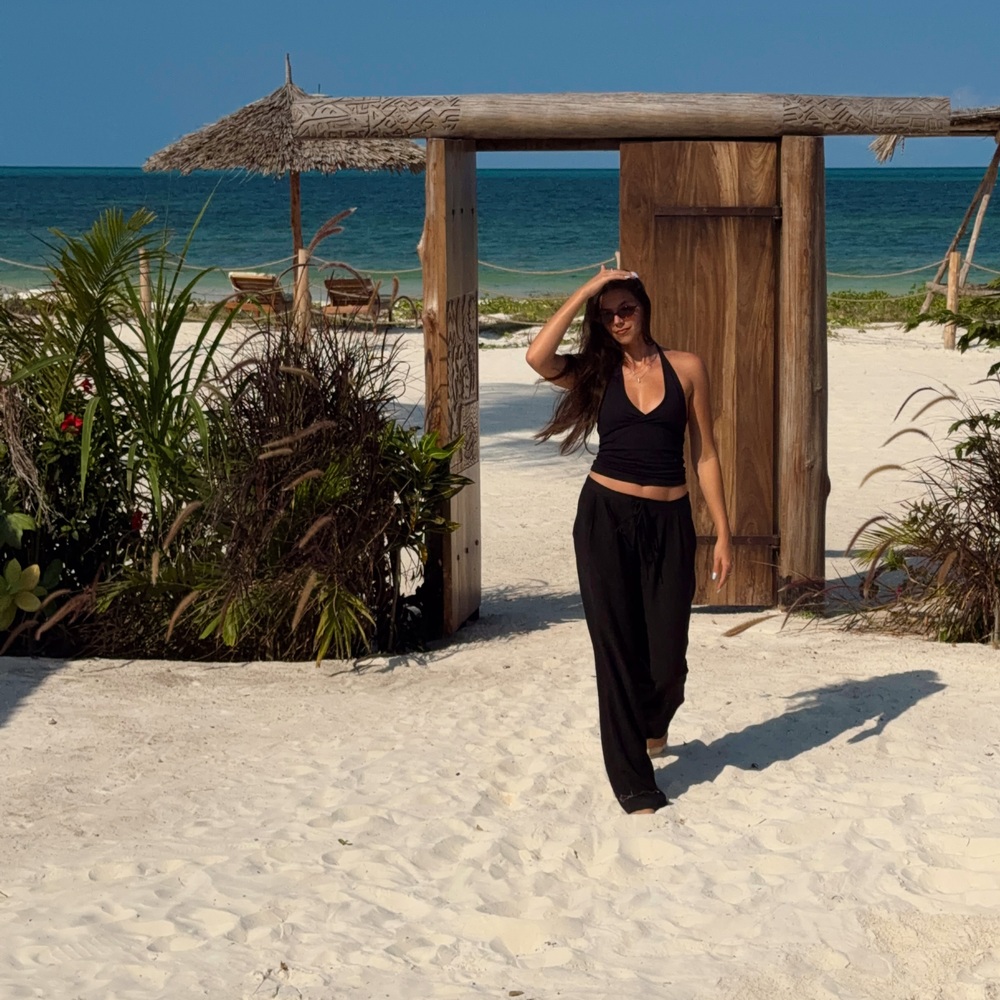 Ellen beside a wooden beach entrance with the ocean behind her in Paje, Zanzibar