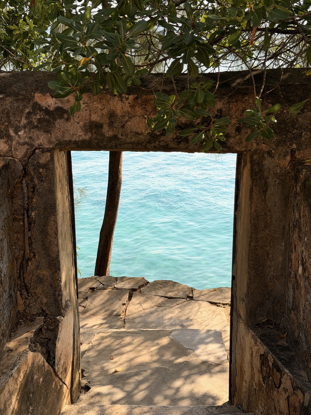 Turquoise water framed by a weathered stone opening on Prison Island, Zanzibar